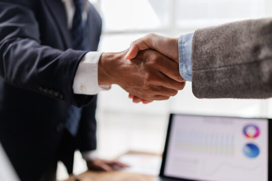 Business partners shaking hands, finalizing a successful deal and agreement, showing cooperation, partnership, and professional collaboration in an office setting