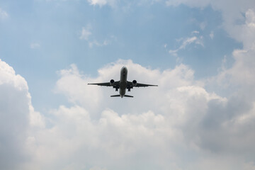 Fototapeta premium Commercial airliner flying overhead against a cloudy blue sky
