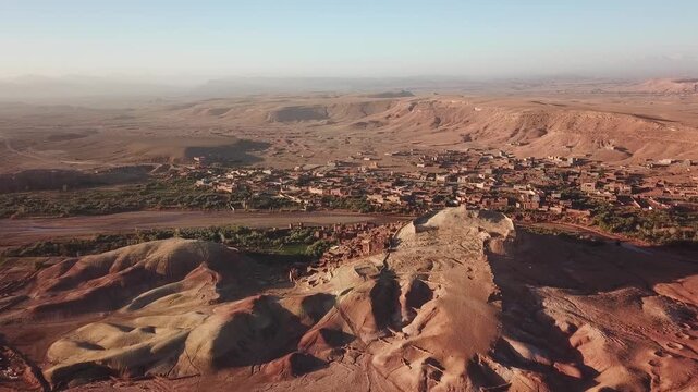 Aerial view of the historic ksar of Ait Benhaddou with its traditional earthen architecture set against the vast arid desert landscape of Ait Benhaddou, Draa-Tafilalet, Morocco.