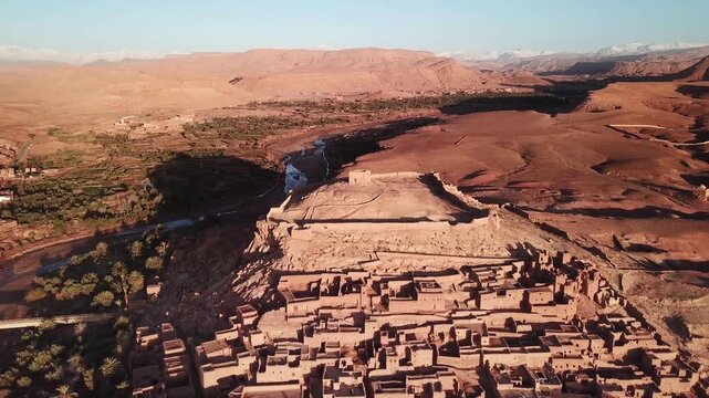 Aerial view of the historic earthen clay ksar of Ait Benhaddou surrounded by desert landscape and a river in Ait Benhaddou, Draa-Tafilalet, Morocco.