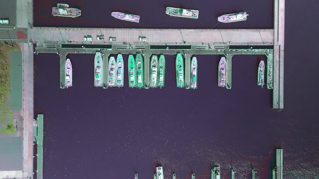 Aerial Top Down View Moving Forward Over Moored Fishing Boats and Pier Structure