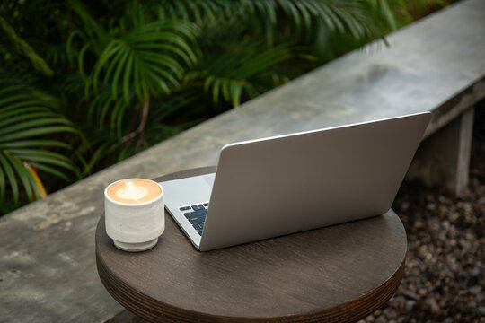 A freelancer enjoys coffee while working on a laptop outdoors