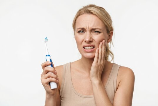 Woman Suffering from Toothache Holding Electric Toothbrush, Dental Pain and Sensitivity Concept