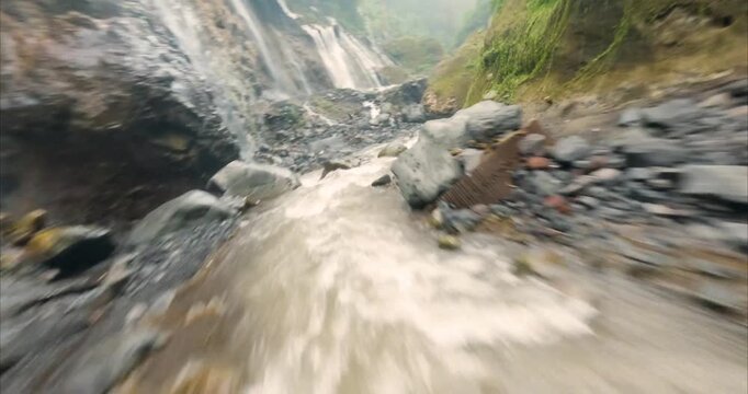 Aerial view of Tumpak Sewu Waterfall with rushing river water flowing through the rocky canyon in Kecamatan Pronojiwo, Jawa Timur, Indonesia.