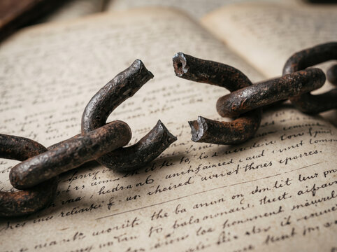 Broken Heavy Iron Chain Links Lying across Antique Manuscript Page