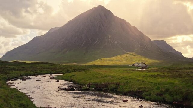 Aerial view of the iconic Buachaille Etive Mor mountain rising above a winding river in the lush green landscape of Glencoe, Scotland, United Kingdom.