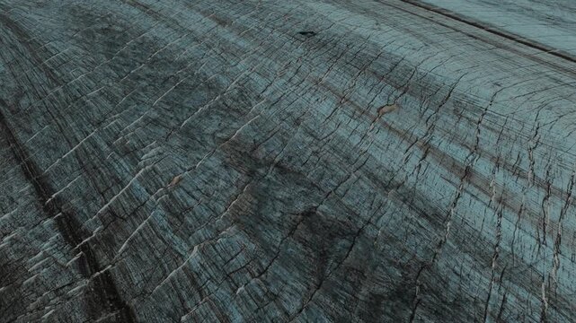 Close aerial view reveals deep cracks and layered textures across an Arctic glacier.