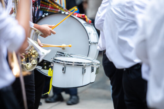 Selective focus to students in a school marching band performing with drums and brass instruments outdoors. Perfect for concepts of music, education, school events, performance, and youth culture.