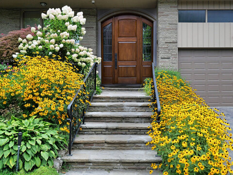 House with elegant wood grain front door with flagstone steps surrounded by flowers