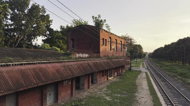 Quiet old platform building beside single railway line at dusk in rural Bangladesh