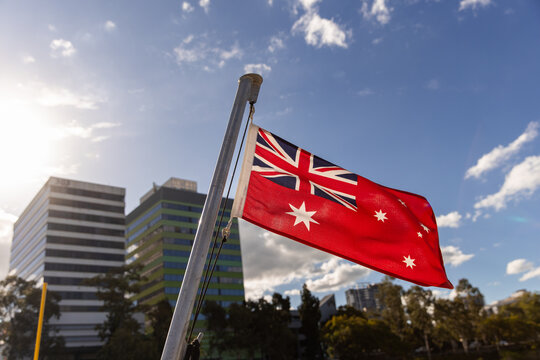 close up of Australian Red Ensign with blue sky and tall buildings in background