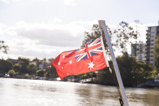 sunlit Australian Red Ensign flapping in the wind off the back of a ferry