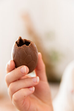 child holding a chocolate easter egg with a bite taken out of it
