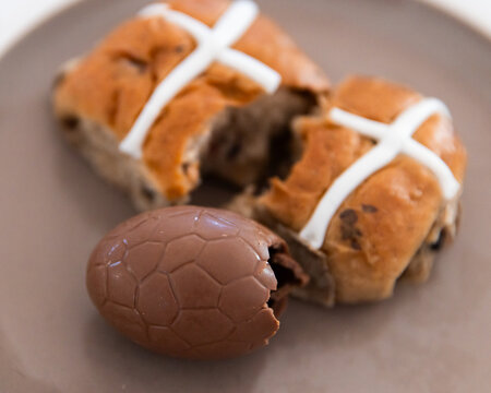 hot cross buns and easter eggs on a plate with bites missing