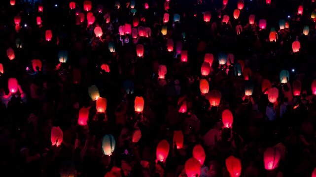 Aerial view of numerous glowing sky lanterns floating in the night sky during the Dieng Culture Festival in Indonesia.