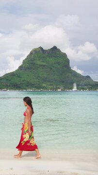French Polynesia Vacation Travel woman walking on paradise motu beach on holidays on Bora Bora with Mount Otemanu. Girl in pareo in Tahiti, French Polynesia. Raw video of real woman without makeup