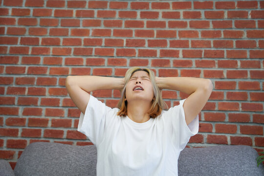 Asian woman is stressed and unhappy, holding her forehead. She has a severe headache or chronic migraine. Concepts of health problems.