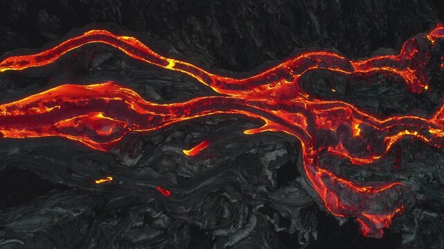 Aerial view of glowing molten lava flowing through volcanic terrain at Kilauea in Hawaii County, Hawaii, United States.
