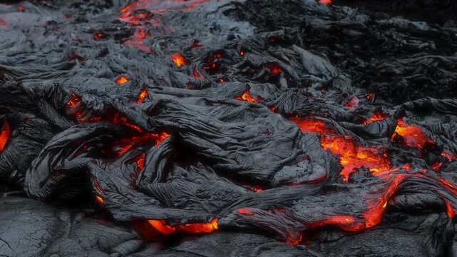 Aerial view of Kilauea volcano lava flow with glowing molten rock and cooling black basalt crust in Hawaii County, Hawaii, United States.