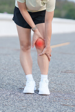 Young adult female runner with knee pain from ACL injury or patellofemoral syndrome. woman having joint ache, ligament tear or patellar tendinitis during running. Sports medical and healthcare concept
