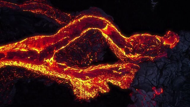 Aerial view of glowing molten lava flowing from Kilauea volcano across the dark volcanic landscape in Hawaii County, Hawaii, United States.