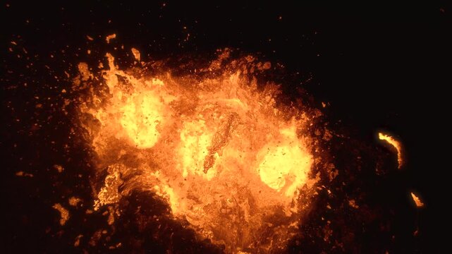 Aerial view of a powerful volcanic eruption with glowing molten lava flowing from the crater and dark volcanic rock in Iceland.