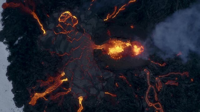 Aerial view of glowing lava streams flowing from an active volcanic eruption across the dark rocky landscape of Iceland.