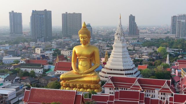 Aerial drone view of giant golden Buddha at Wat Paknam temple with Bangkok skyline in the background. Iconic religious landmark in Thailand.