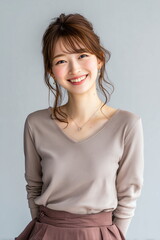 Obraz premium Happy Young Japanese Woman Smiling in Elegant Casual Outfit Against Neutral Background