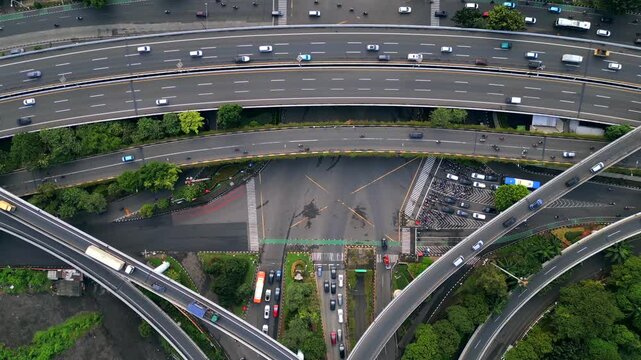Aerial view of multilayer highway and busy intersection in Jakarta, Indonesia. Urban transport system with flyovers, cars, motorbikes, and complex road infrastructure.