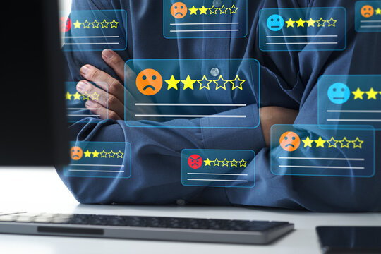 Low customer satisfaction and negative online reviews. Businessman worried about poor ratings and feedback on a desktop computer with crossed arms.