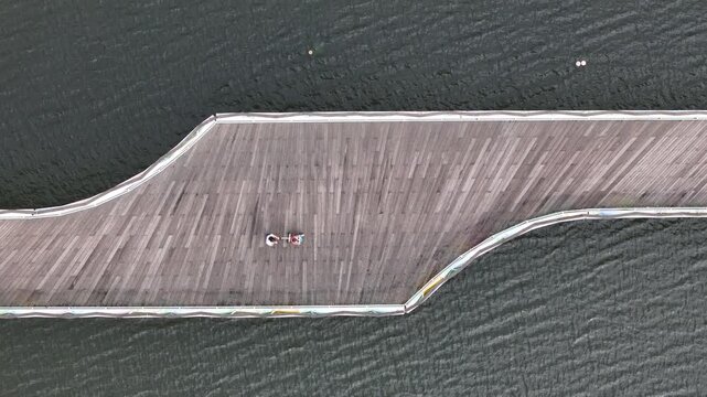 Aerial view of a person with a pushchair walking on a wooden pier over the river in Coimbra, Coimbra District, Portugal.