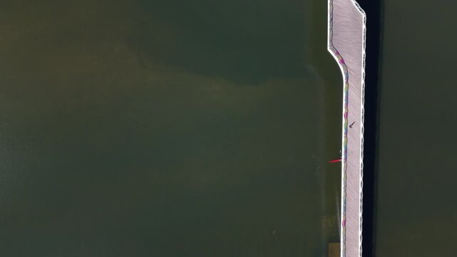 Aerial view of a lone rower in a red boat on the calm waters of the Mondego River in Coimbra, Coimbra, Portugal.