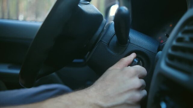 Close up man hand inserting key in ignition, turning to start vehicle engine before driving, with dashboard lights illuminating in car interior. Male driver inserting ignition key, starting car engine