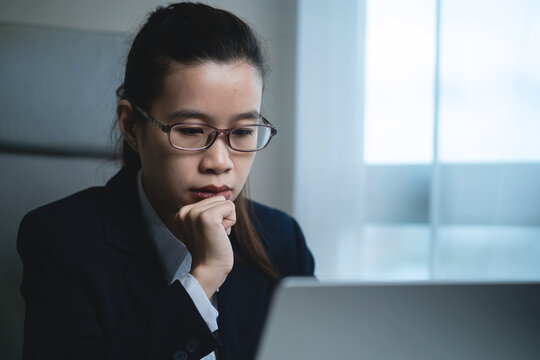 Businessman Working on Laptop at Modern Office Desk While Showing Signs of Stress, Fatigue and Difficulty Managing Work Tasks