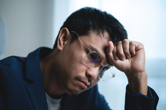 Stressed Businessman Sitting at Office Desk and Holding His Head While Working on Laptop, Showing Workplace Pressure and Frustration