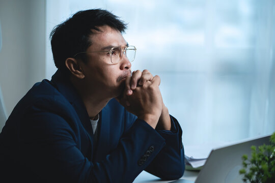 Stressed Businessman Sitting at Office Desk and Holding His Head While Working on Laptop, Showing Workplace Pressure and Frustration