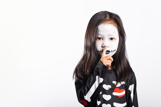 Halloween costume on young kid wearing spooky face paint while smiling against white isolated background for autumn holiday celebration party portrait
