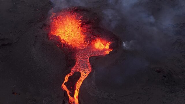 Aerial view of glowing lava flowing from a volcanic crater with smoke and ash in Reykjavik, Reykjavikurborg, Iceland.