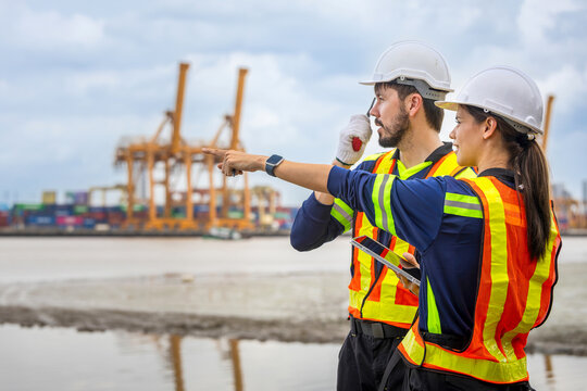 Port engineers pointing and working at container shipping terminal, Logistic managers with walkie talkie and tablet discussing cargo port operations, Industrial workers team inspecting shipping yard