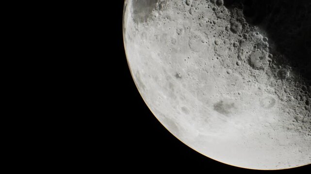 A close view of the moon at night shows its surface features and craters. The scene captures the beauty of the moons texture and shadows in the dark sky.