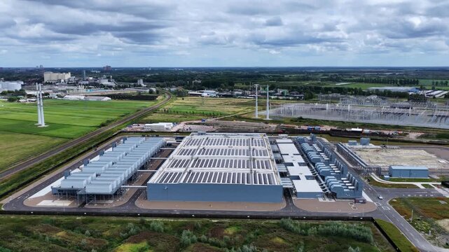 Aerial view of the Google Data Center facility featuring large rooftops with solar panels surrounded by green fields and power infrastructure in Groningen, Groningen, Netherlands.