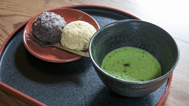 黒いお椀に入った点てたての抹茶と小皿に添えられた粒あんと黄粉の2種のおはぎ