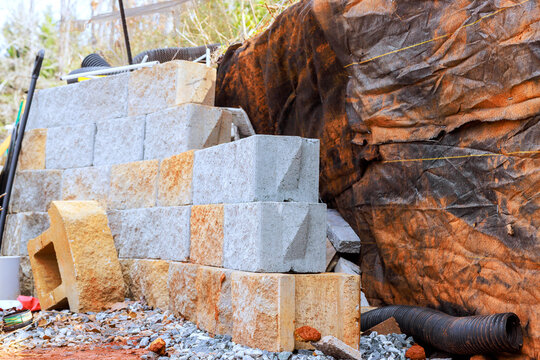 Blocks are retaining wall at construction site with gravel on ground scattered around