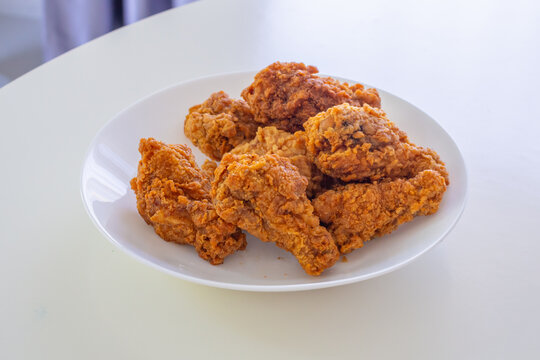 Crispy spicy fried chicken in white plate on wood table