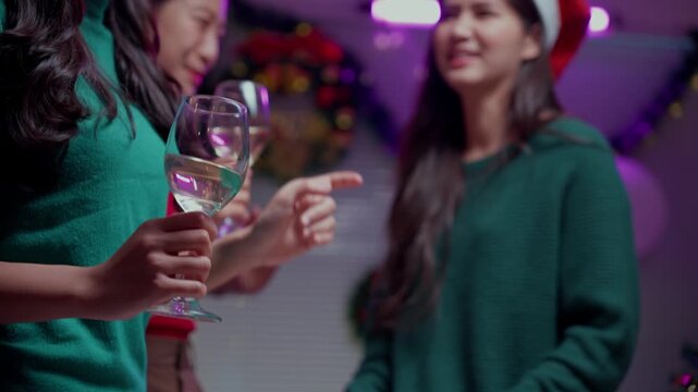 Asian friends dancing and drinking wine during Christmas eve holiday celebration at home with happy emotion