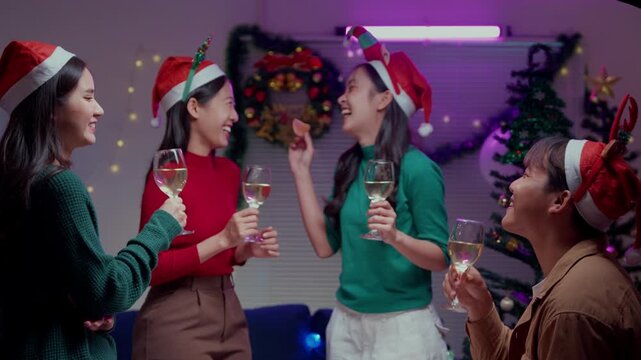 Asian friends celebrating Christmas eve with wine and confetti at a festive home party with neon lights