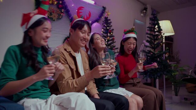 Cheerful friends celebrating christmas together, laughing and toasting with white wine during a New Year's Eve party at home