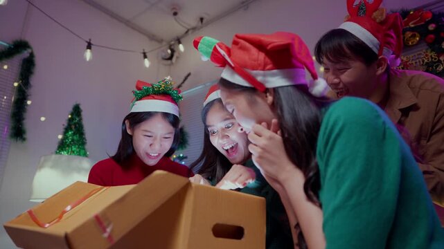Surprised friends opening a glowing Christmas gift box together. Happy celebration with magic light