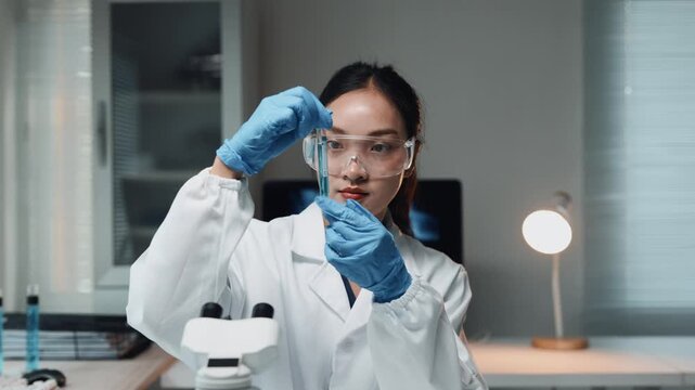 Asian scientist mixing chemical liquid in test tube for pharmaceutical research and biotechnology development in laboratory